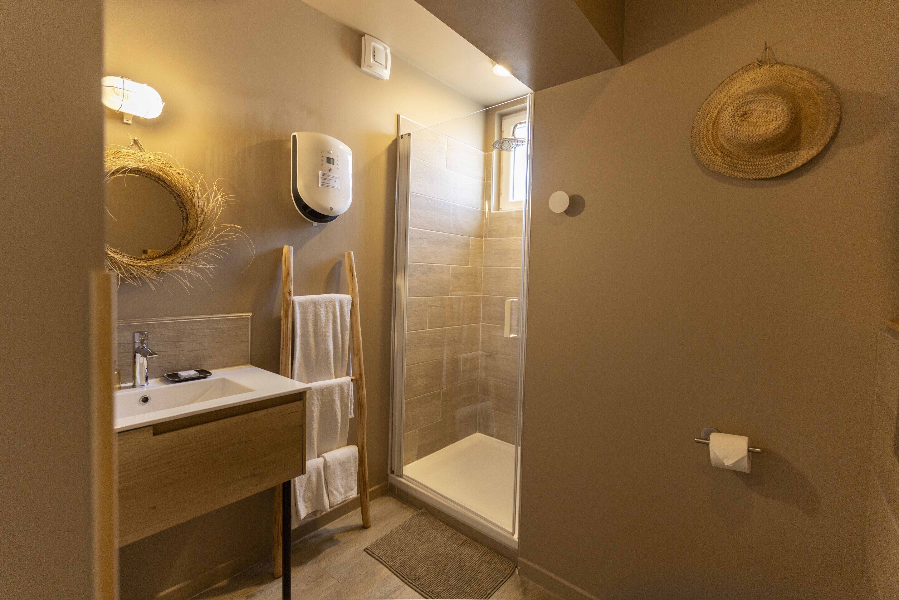 A modern bathroom with a glass-enclosed shower, a wooden vanity, and a towel rack.