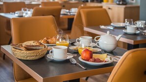 Une table mise pour le petit-déjeuner, avec des tables, des chaises et une variété d'aliments, notamment du pain, du jus et des œufs.