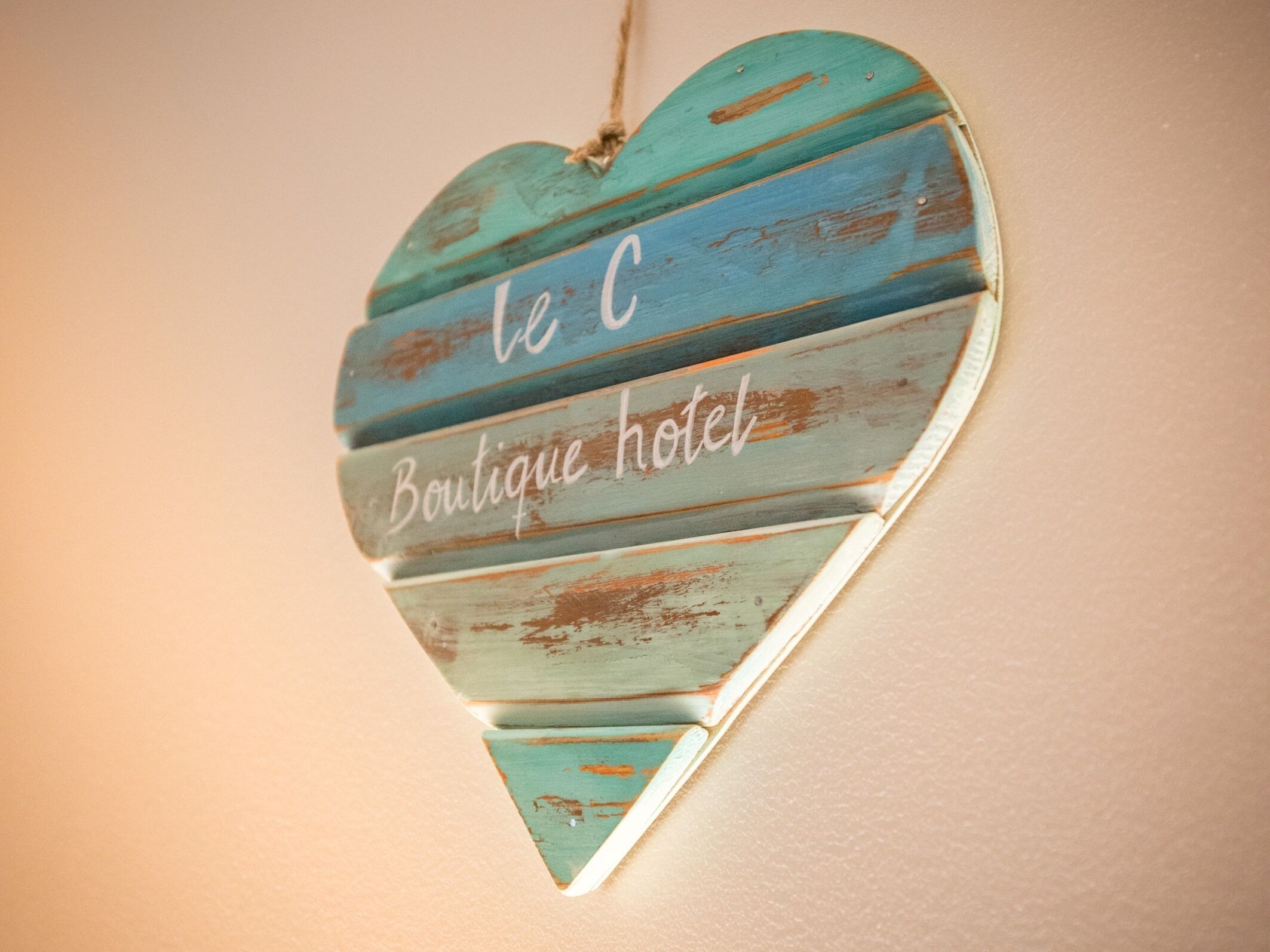 Een hartvormig bord met de tekst 'le C Boutique hotel' aan een muur bevestigd.