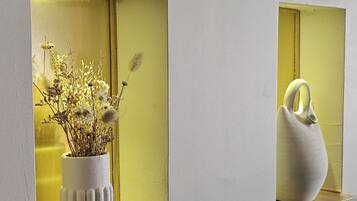 Deux vases blancs ornés de fleurs séchées sont posés sur des étagères, le tout adossé à un mur.