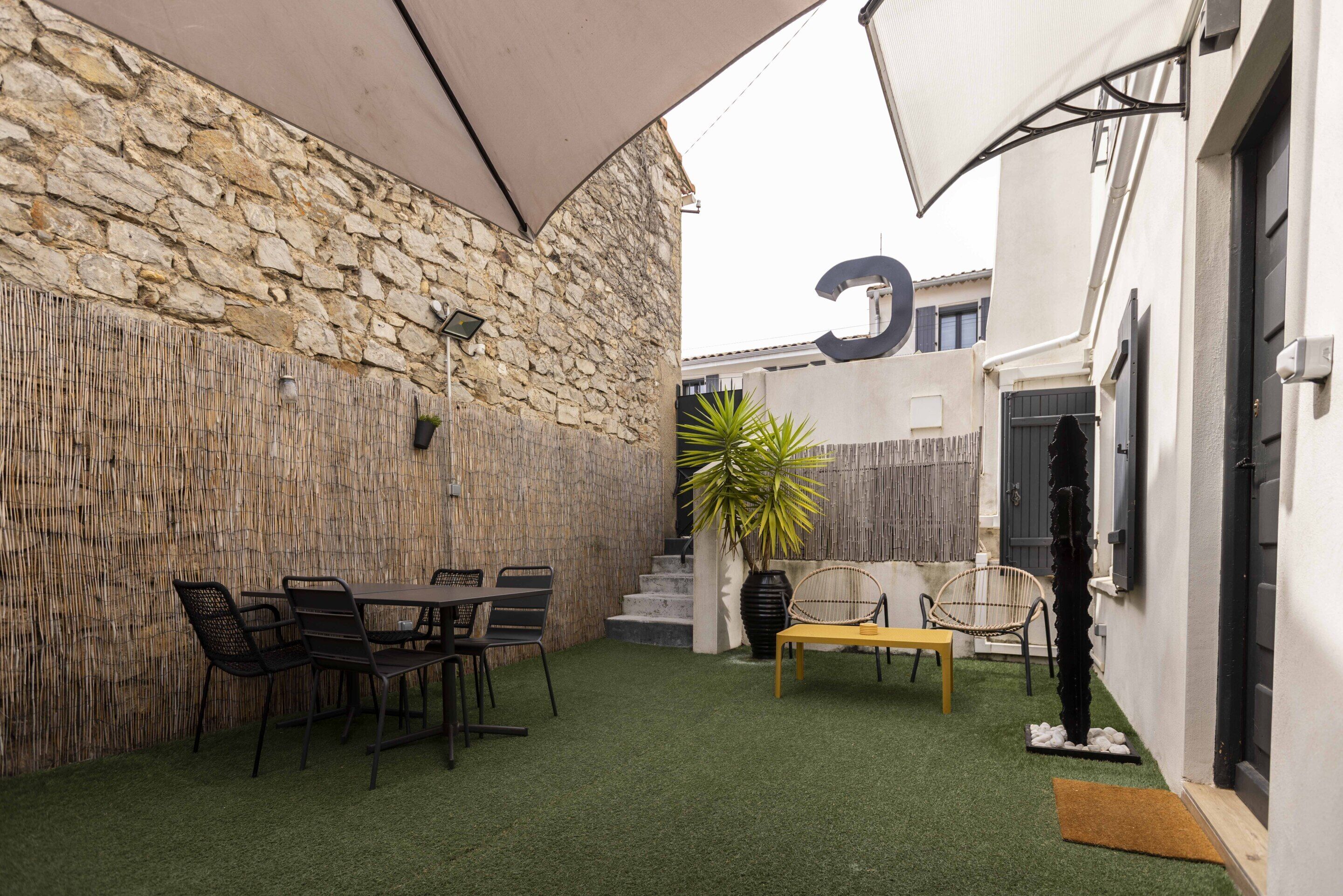 Un patio con un muro de piedra, una mesa con sillas y un banco.