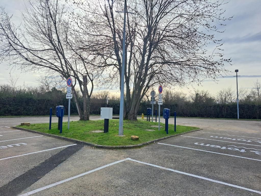 A parking lot with marked spaces and a central island with trees and a signpost.