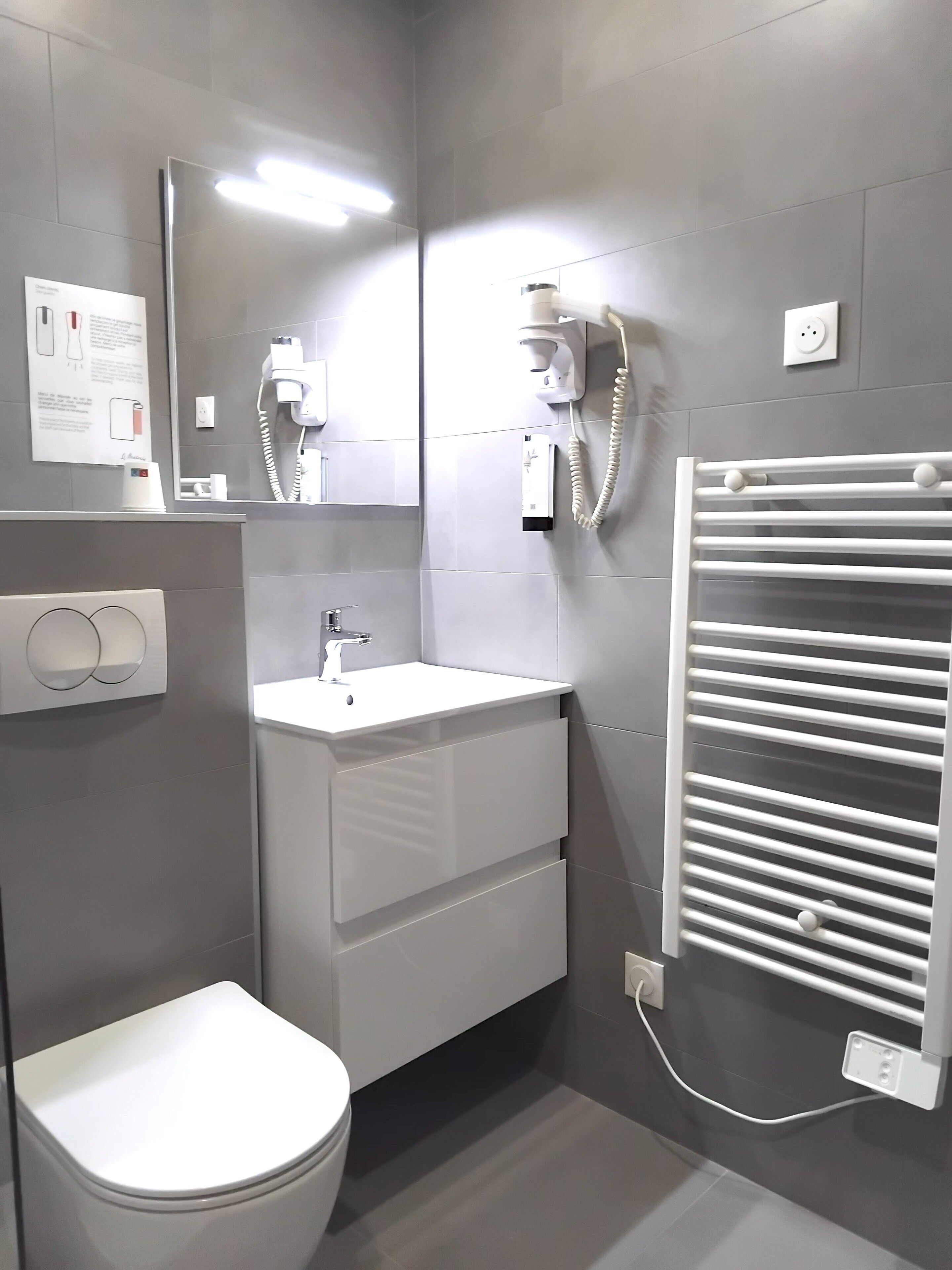 Un baño moderno con inodoro, lavabo, espejo y toallero.