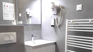Un baño moderno con inodoro, lavabo, espejo y toallero.