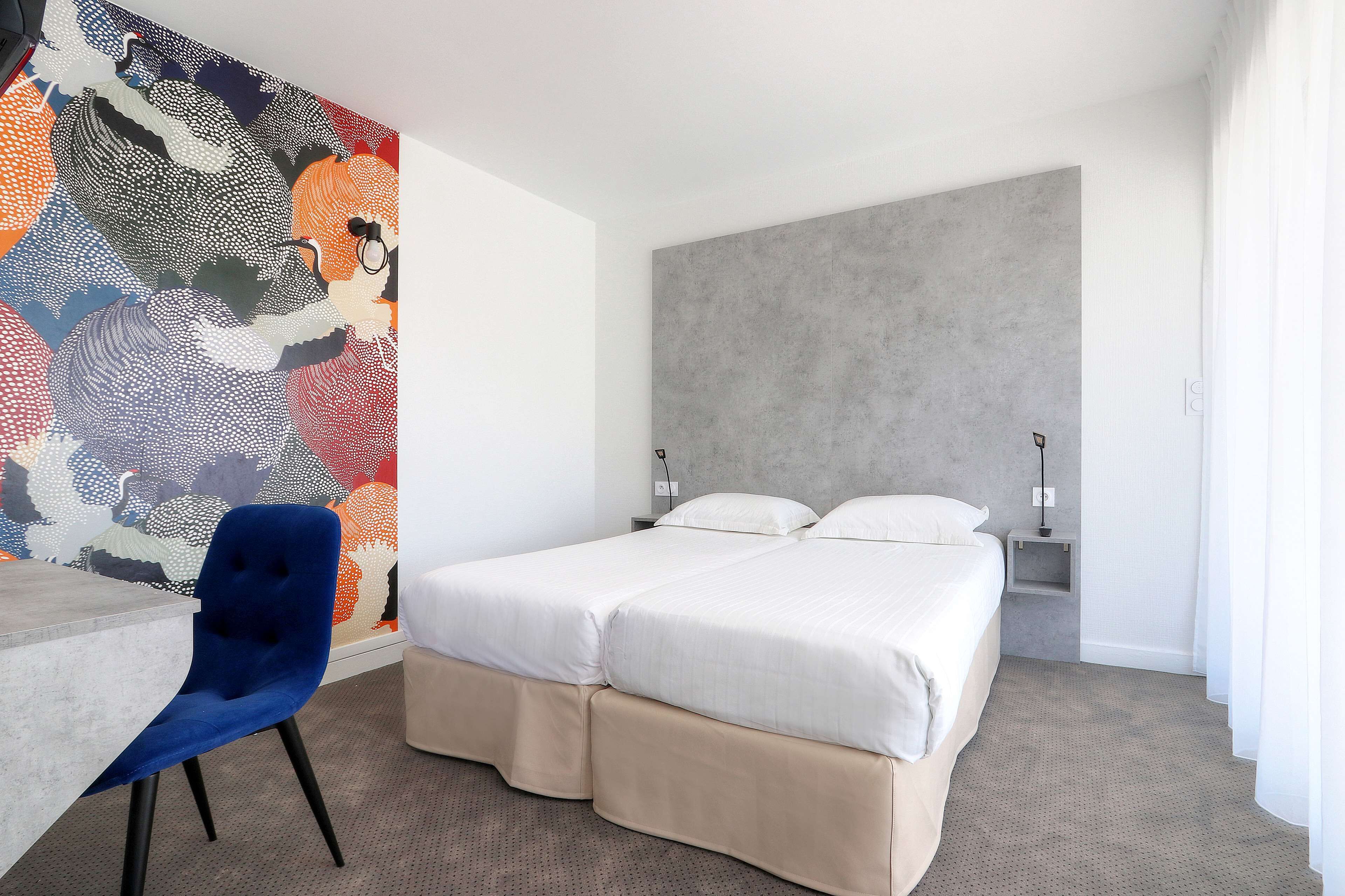 Una habitación de hotel moderna con una cama grande, un escritorio y una obra de arte abstracta y colorida.