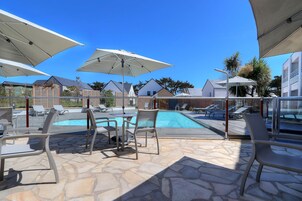 Una piscina al aire libre, sillones reclinables de piscina
