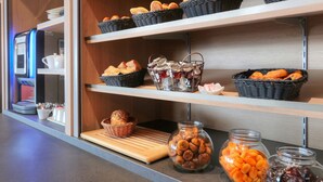 A buffet area with shelves stocked with bread, pastries, and jars of spreads. - Best Western Hotel Le Bellevue (Quiberon)