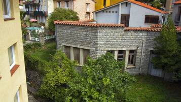 A courtyard with outdoor seating, surrounded by buildings with red-tiled roofs and a mix of stone and plaster exteriors.