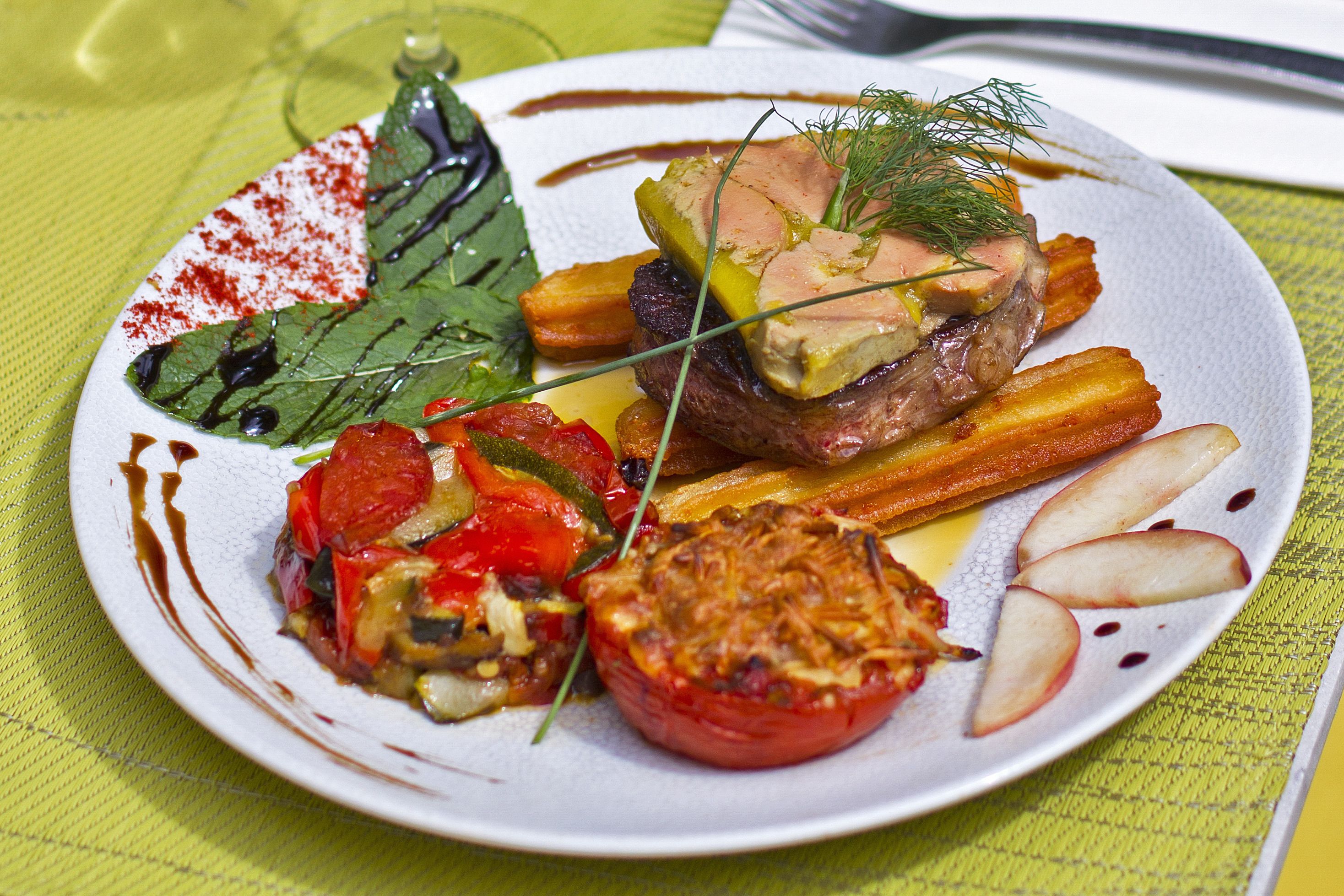 Un plato de comida con varias verduras y un trozo de carne.