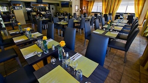 A restaurant with multiple tables set for dining, chairs, and a bar area in the background. - Hôtel Princess (Vernet-les-Bains)