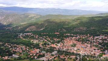 A town nestled in a valley with red-roofed buildings and green hills in the background.