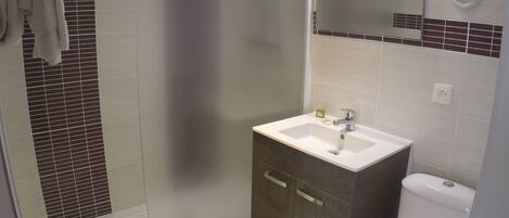 A bathroom with a shower, toilet, and sink.