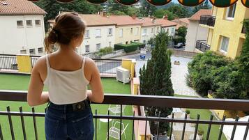 Un balcon donnant sur un quartier résidentiel, avec vue sur des maisons et une enseigne d’hôtel.