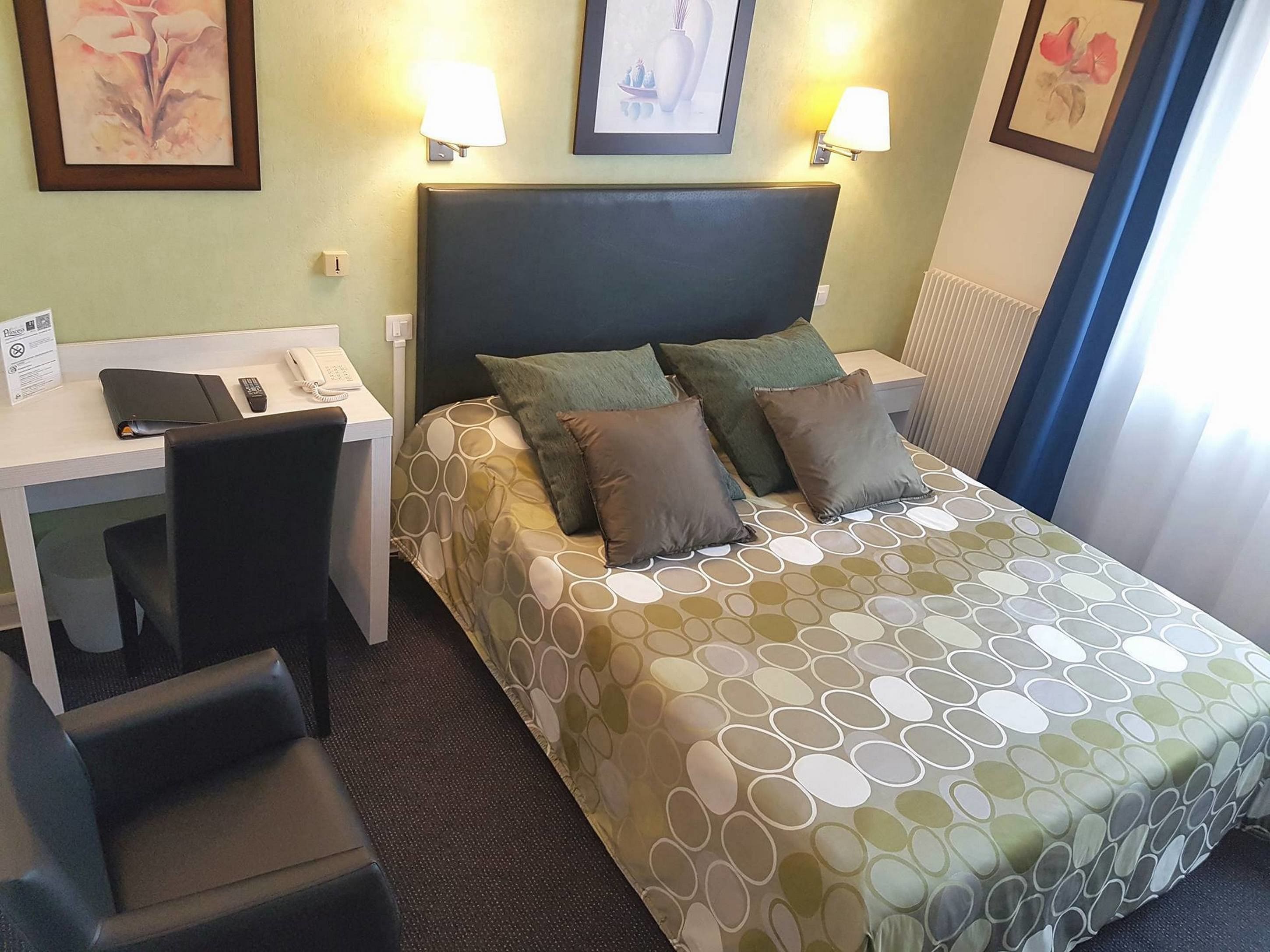 Una habitación de hotel con cama, escritorio, silla y teléfono.