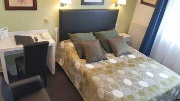 Una habitación de hotel con cama, escritorio, silla y teléfono.