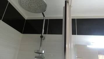 A shower with a rain showerhead, a handheld showerhead, and a wall-mounted control.