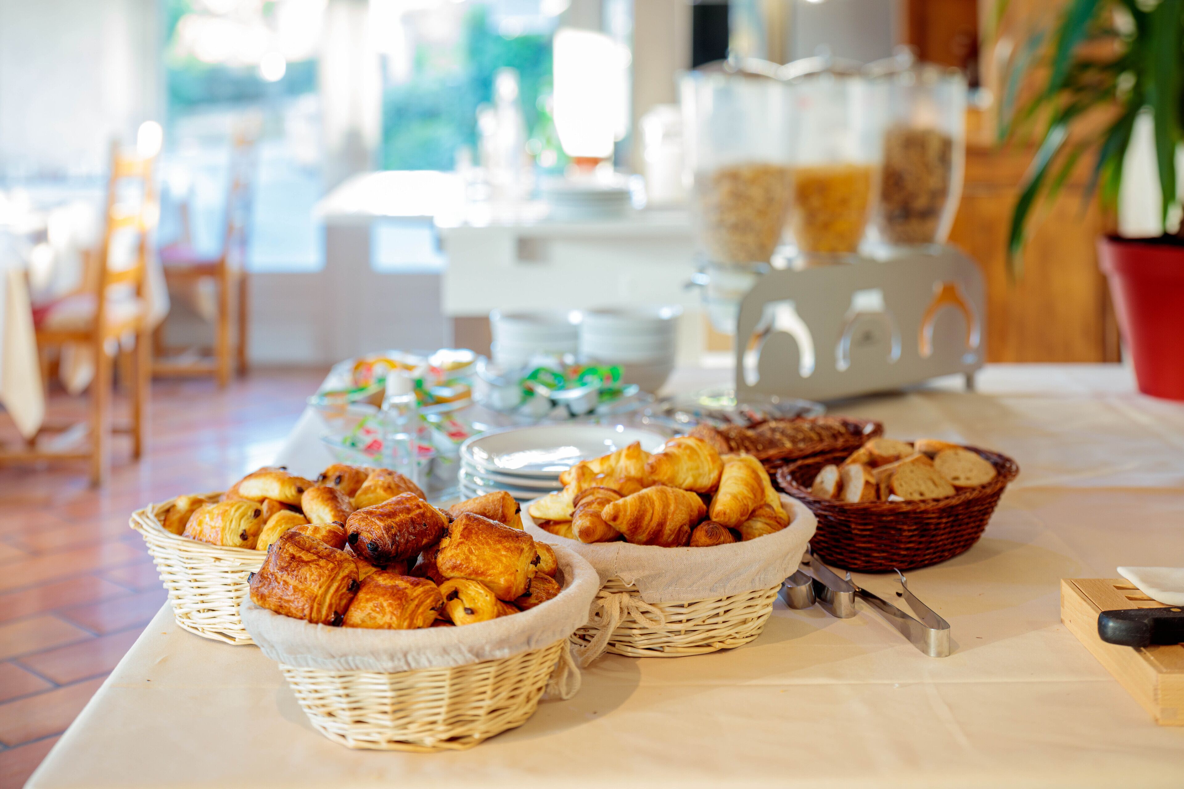 A buffet table with various baked goods and utensils.