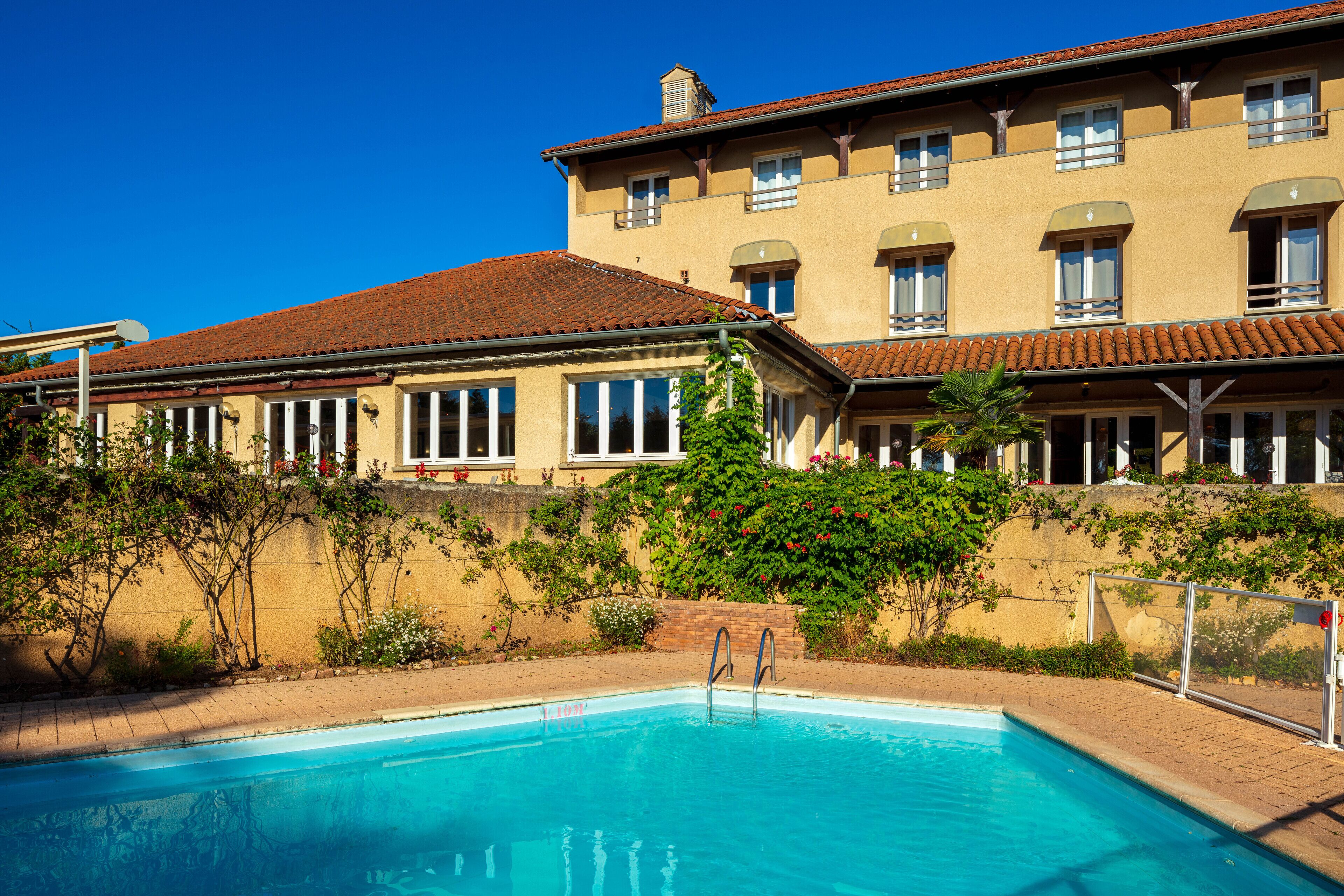 A swimming pool with a clear blue water, surrounded by a building with multiple windows and balconies.