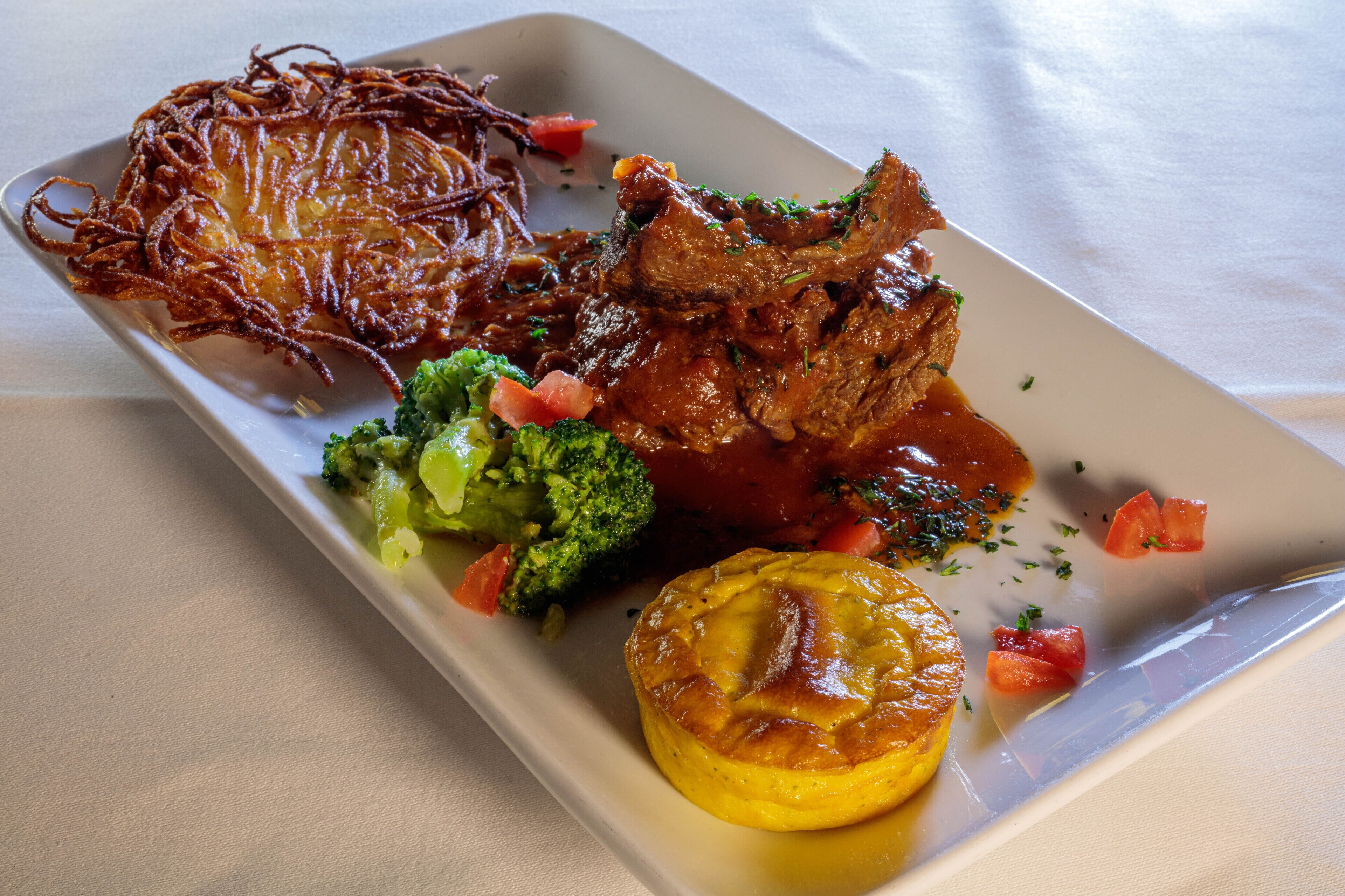 A rectangular plate with a variety of food items including a piece of meat, vegetables, and a fried item.