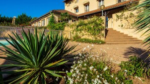 A building with a pool, surrounded by greenery and stairs leading to the entrance. -  Logis Hotel Noemys Morgon (Villie-Morgon)