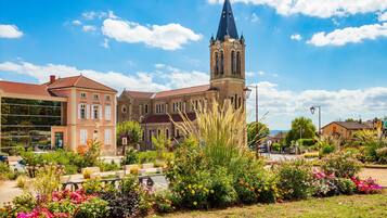 Une église historique dotée d’un clocher imposant, entourée d’un jardin bien entretenu où poussent diverses plantes et fleurs.