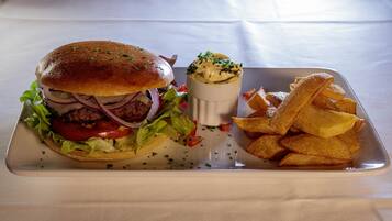 Eine Mahlzeit mit einem Burger, Pommes und einer Soße auf einer weißen Tablett.