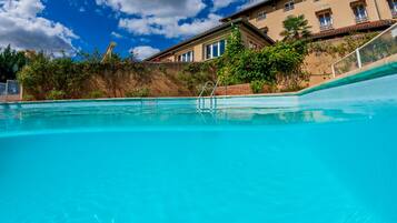 Une piscine à l’eau d’un bleu cristallin, entourée d’un bâtiment doté de nombreuses fenêtres et d’un mur en briques.