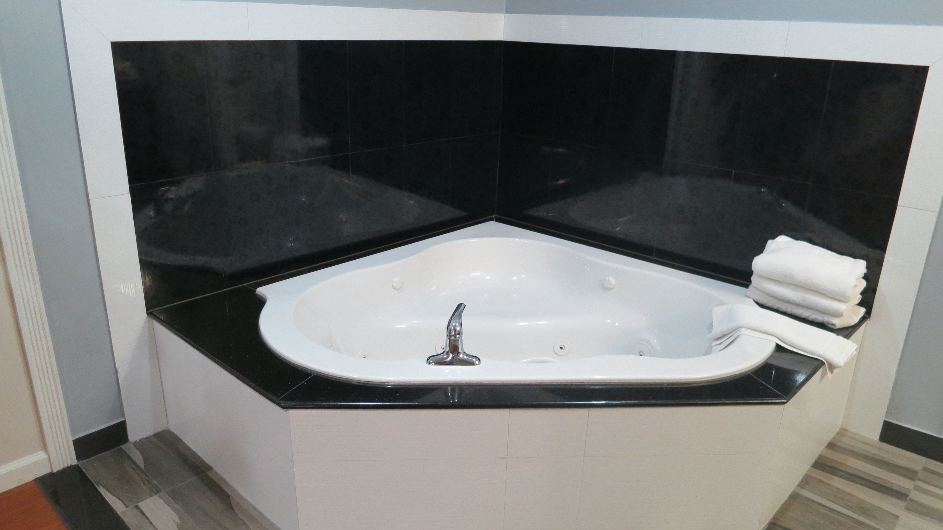 A modern bathroom with a freestanding bathtub, black countertop, and white tiles.