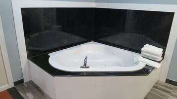 A modern bathroom with a freestanding bathtub, black countertop, and white tiles.