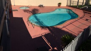 Une piscine sur le toit, divisée en deux zones distinctes, entourée d’une terrasse rouge et d’une clôture blanche.