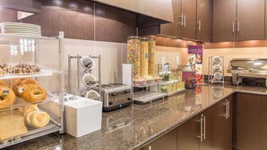 A breakfast buffet area with various food items, a coffee machine, and a toaster.