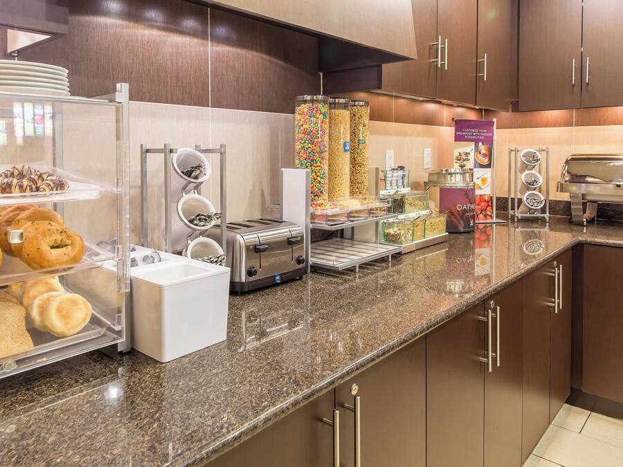 A breakfast buffet area with various food items, a coffee machine, and a toaster.