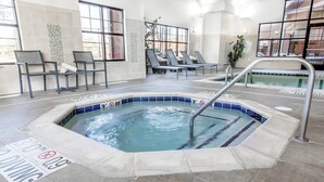 A hot tub area with lounge chairs, a pool, and a sign indicating a 30-minute no diving rule.