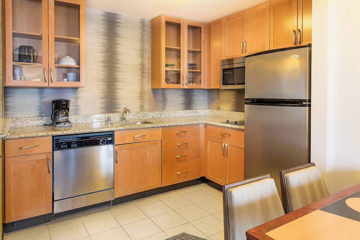 A kitchen with wooden cabinets, stainless steel appliances, and a granite countertop.