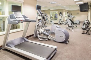 Une salle de sport équipée de tapis de course, de vélos elliptiques et de matériel de musculation.