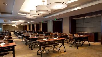 A conference room with multiple tables, chairs, and overhead lighting.