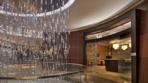 Un hall d’entrée moderne avec une rambarde en verre, un luminaire suspendu et un comptoir d’accueil.