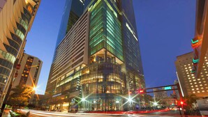 Un immeuble de grande hauteur doté d’une façade moderne en verre, entouré d’autres bâtiments imposants.