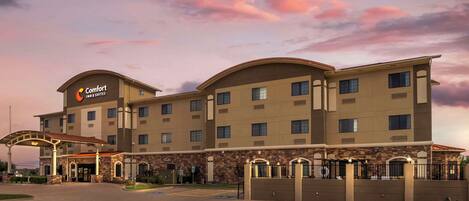 A Comfort Inn Suites hotel with a stone facade, multiple balconies, and a covered entrance.