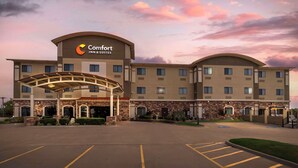 Un hotel Comfort Inn & Suites amb entrada coberta, diverses plantes i un pàrquing.