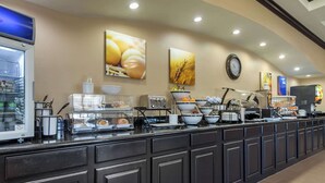 Zona de buffet amb diferents estacions de menjar, un frigorífic i decoració a les parets.
