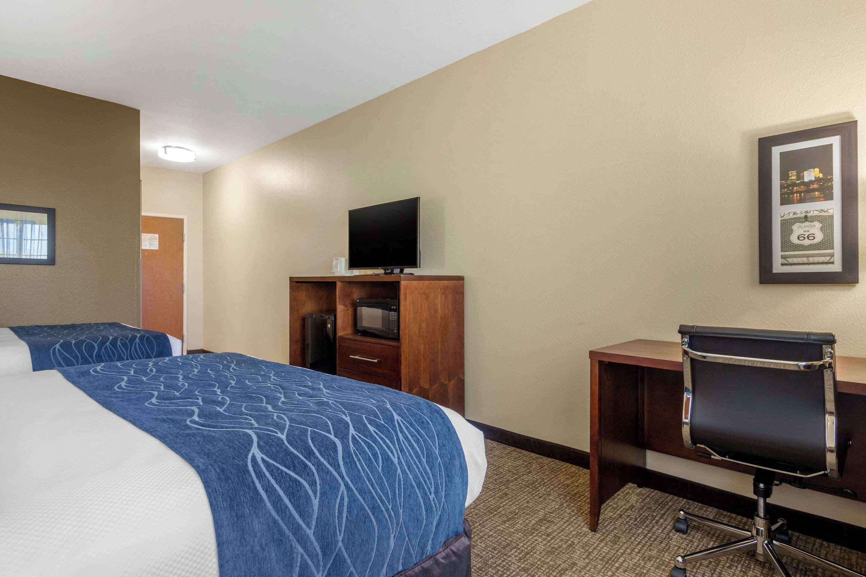 Habitación de hotel con una cama grande, un escritorio con silla, un televisor y un cuadro en la pared.