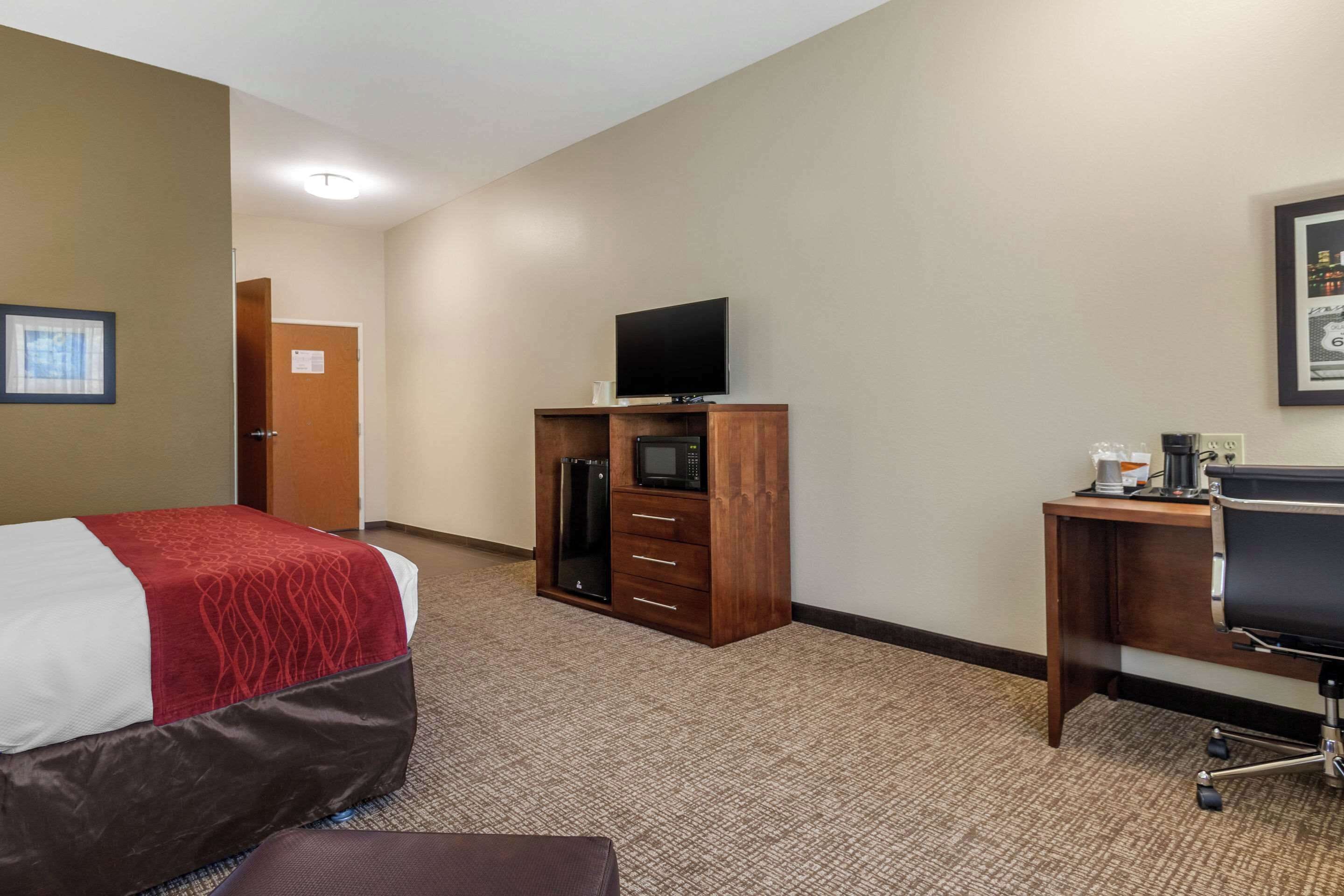 A hotel room with a bed, a desk, a television, a microwave, and a refrigerator.