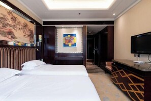 Una habitación de hotel con una cama, televisión, un cuadro y decoración en la pared.