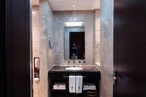 Un baño moderno con lavamanos de mármol, un espejo y un perchero para toallas.