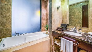 Un baño moderno con una bañera grande, un lavamanos y un espejo.