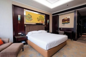 Een hotelkamer met een groot bed, een bureau, een stoel en een bank.
