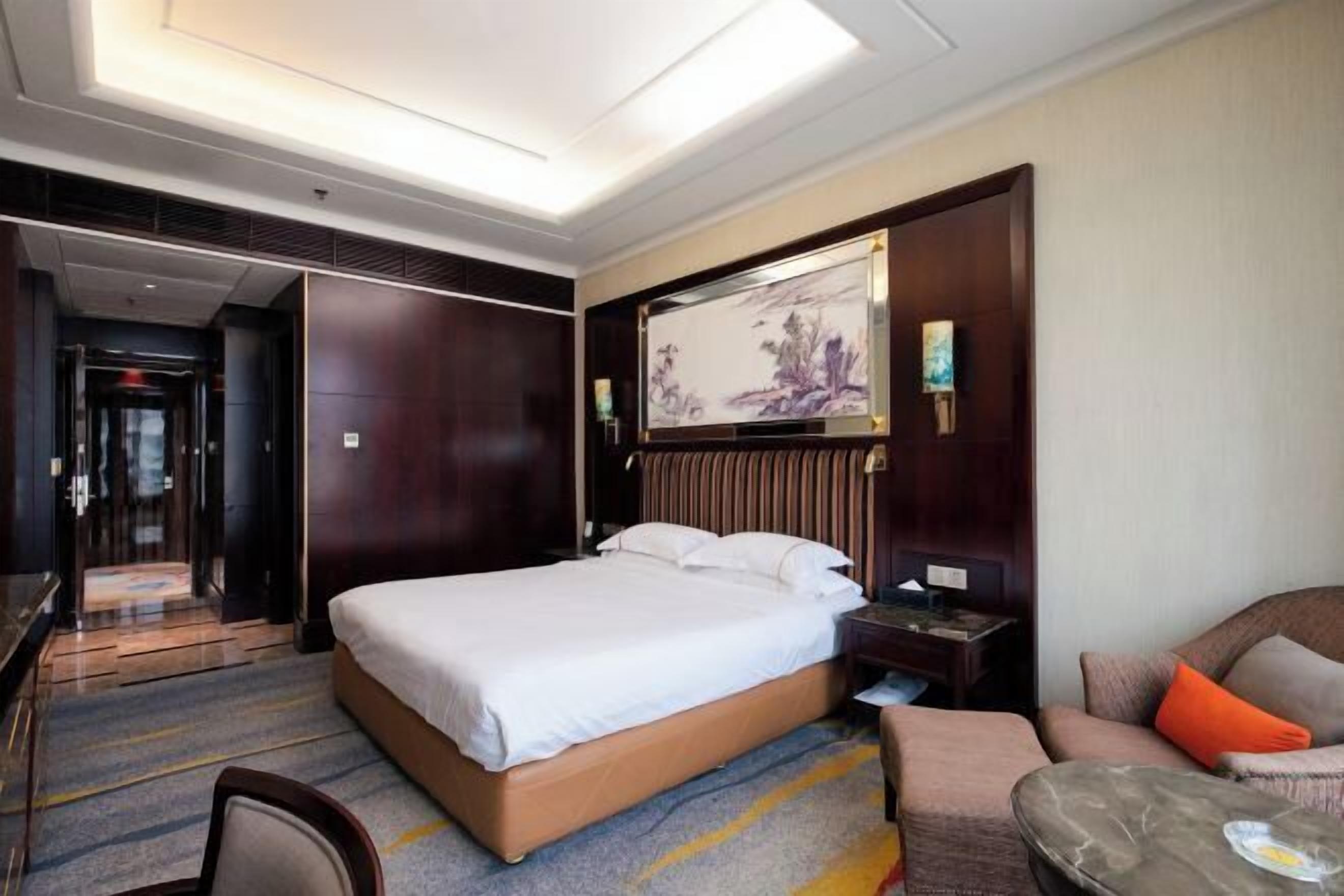 Een hotelkamer met een groot bed, een bureau, een stoel en een klein tafeltje.