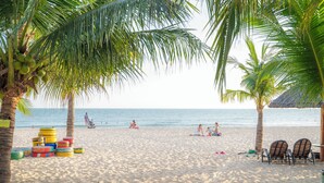 Una playa con palmeras, juguetes de playa coloridos y algunas personas relajándose.