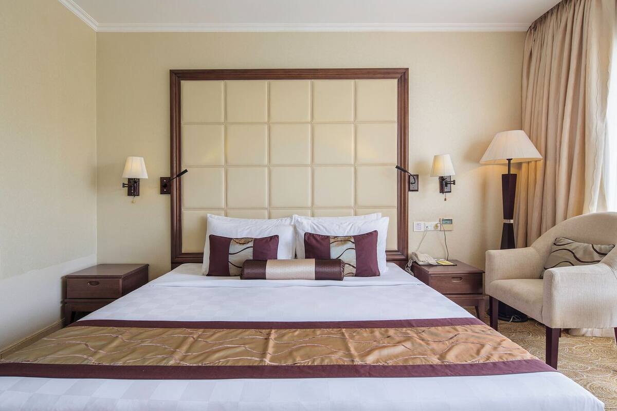 Een hotelkamer met een groot bed, twee nachtkastjes, een stoel en een bijzettafeltje.